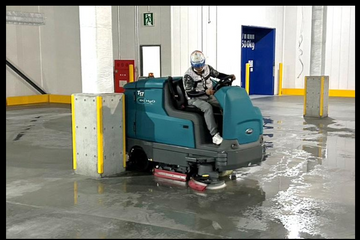 Ride-on floor scrubber cleaning an industrial floor